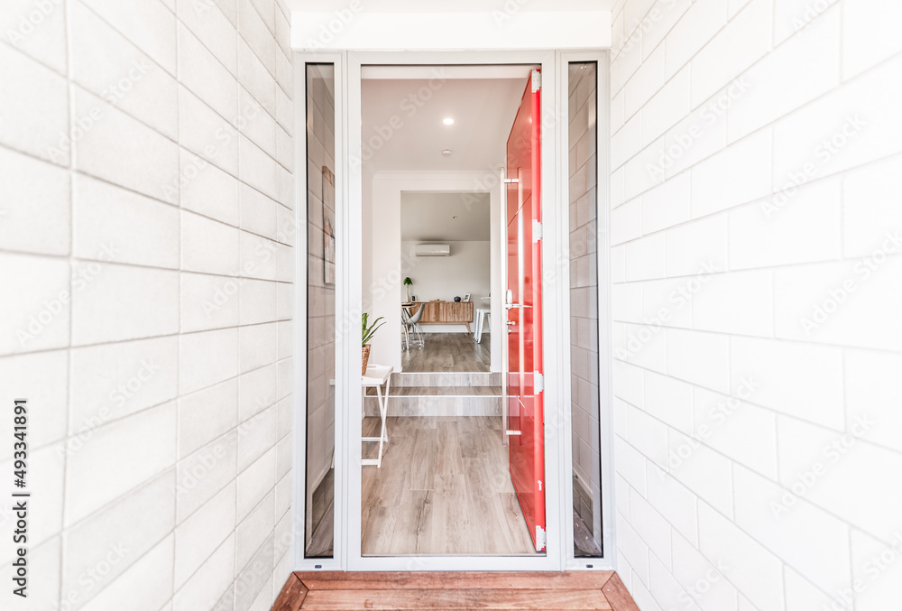 interior of a modern house looking in through the entrance front red door wood floors white tile and brick