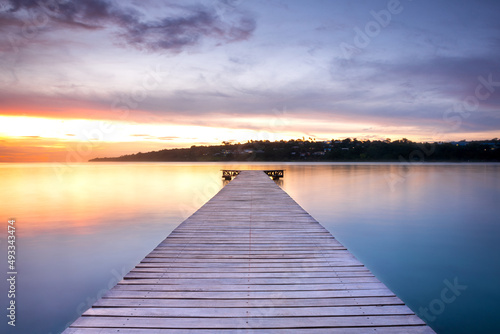 Fototapeta Naklejka Na Ścianę i Meble -  Wooden pontoon over the water sunset long exposure