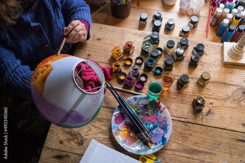 someone's hand painting a white lampshade