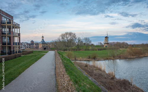 Pedestrian path along the historical fortifications in dutch city of Gorinchem with a view on windmill and an old city gate photo