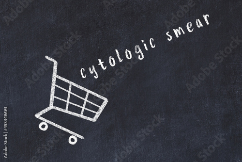 Chalk drawing of shopping cart and word cytologic smear on black chalboard. Concept of globalization and mass consuming photo