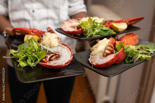 Waiter holding lobsters with mayonnaise on a plate