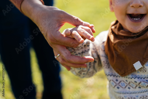 Faceless parent holding hand of toddler boy photo