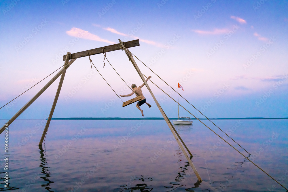 Boy Jumping Into Lake from Swing at the Cottage Boy Jumping Into Lake from Swing at the Cottage