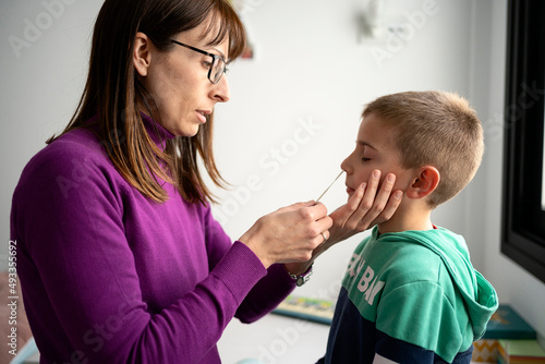 Mom doing nasal COVID 19 test to son photo
