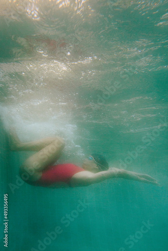 Woman in a red sports swimsuit swims in the pool photo