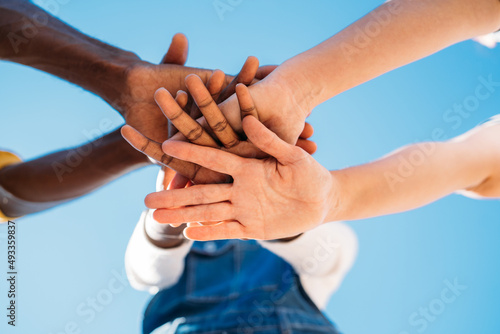 Crop multiracial people stacking hands together