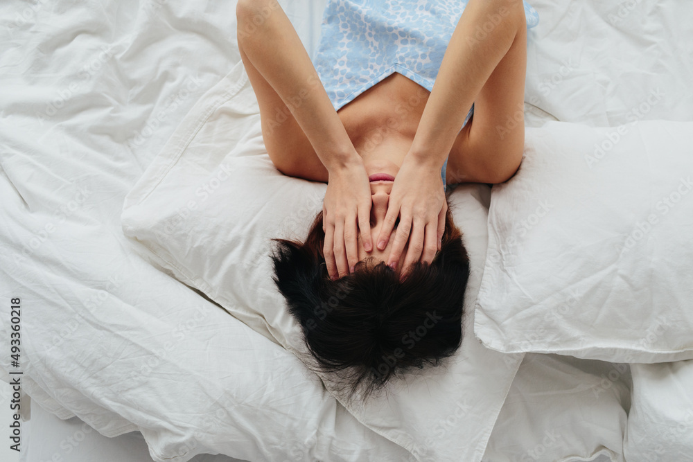 Sad woman with headache lying on bed Sad woman with headache lying on bed