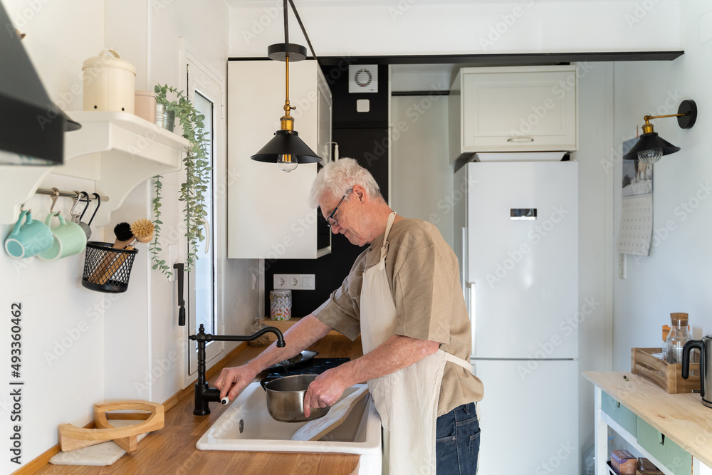 Senior man filling cooking pot with sink faucet water Senior man filling cooking pot with sink faucet water