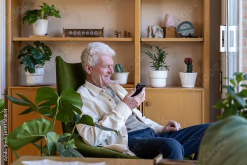 Senior man talking on mobile phone at home photo