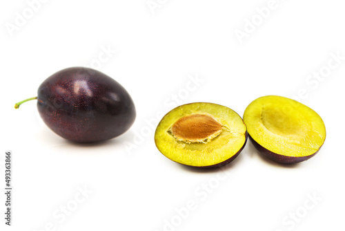 Ripe fresh organic plum whole and cut in half isolated on white background.