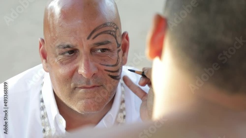 Bald man being painted with traditional Face painting, Close up. Hawaii photo