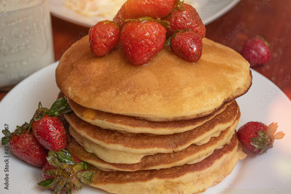 Plate of hot cakes and strawberries on a table Plate of hot cakes and strawberries on a table