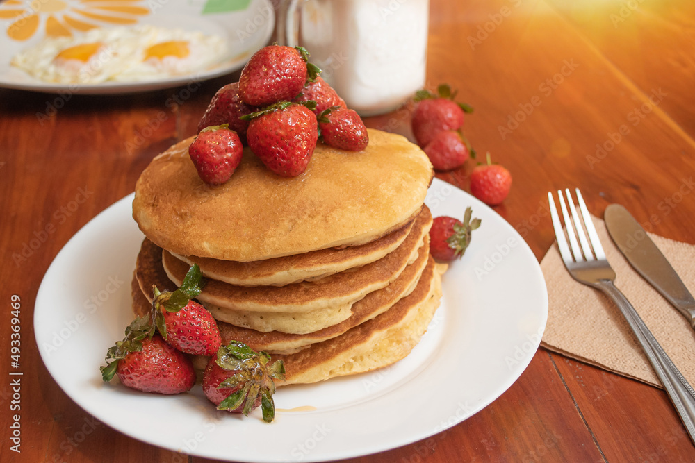 Plate of hot cakes and strawberries on a table Plate of hot cakes and strawberries on a table