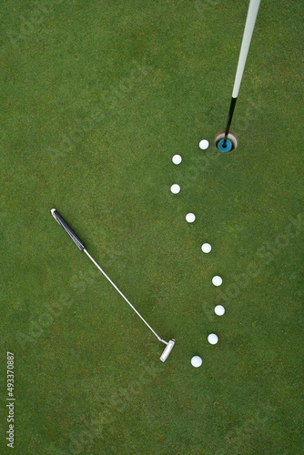 Putting green with line of golf balls and putter