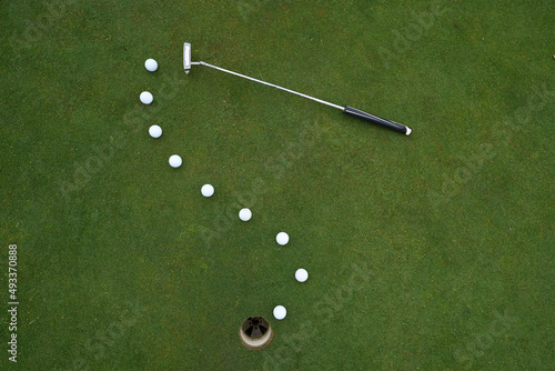 Golf putter and balls at the hole photo