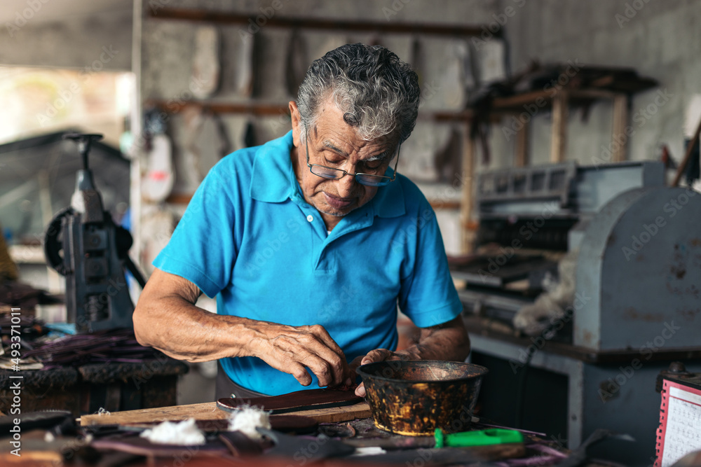 Senior shoemaker dyeing some soles Senior shoemaker dyeing some soles