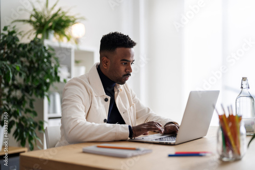 Arab man doing online work on laptop photo