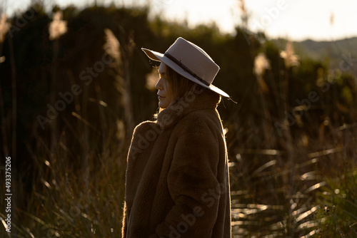 A pensive woman in a hat and warm clothes in the countryside.