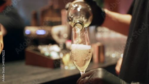 Waiter is pouring champagne in the glass, close-up. Party at the restaurant 