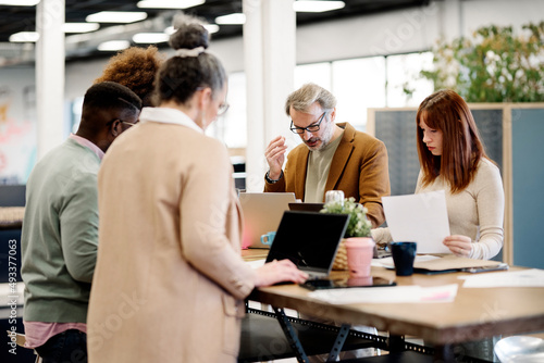 Focused diverse colleagues working on project at table photo