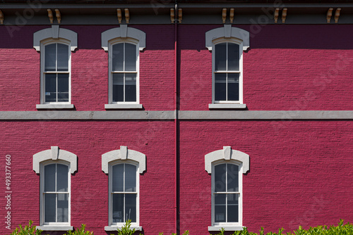 An old magenta brick building with white windows  photo