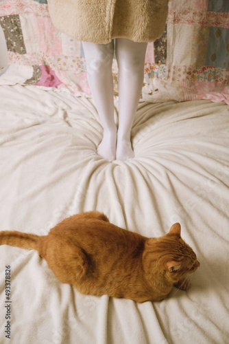 Girl and orange cat in bed
