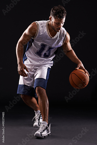 Dribbling pro. Studio shot of a basketball player against a black background. © Duncan M/peopleimages.com