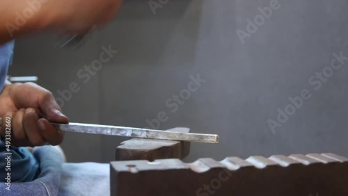 silversmith beating silver bar with hammer
 photo