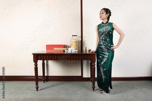 Beautiful young woman wearing modern Chinese style dress cheongsam fashion retro vintage table room photo