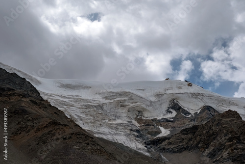 Glacier on rocky mountains. Melting glaciers due to global warming climate change problem. Barskoon mountain pass. Travel tourism in Kyrgyzstan concept.