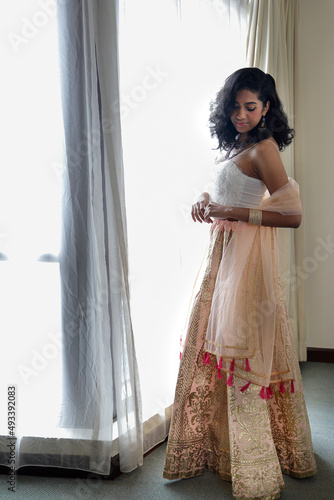 Beautiful young woman wearing Indian style royalty dress jewellery light makeup retro vintage fashionnext to window light photo