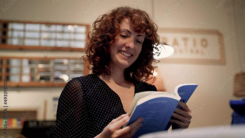 Pretty Young Curly Woman Commenting And Laughing At Book Reading