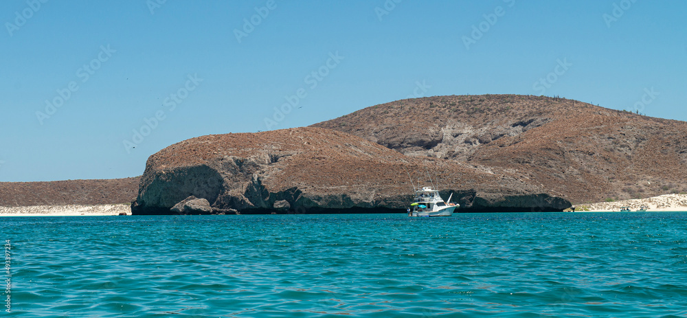Fototapeta premium Nautical vessel sayiling on the Sea of cortes in Baja California Sur. Mexico. with mountains and clouds in the background and a beautiful sunny summer morning with blue sky