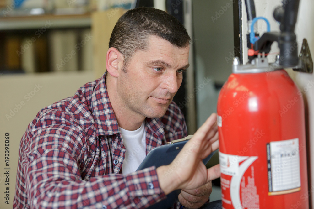 male technician checking red fire extinguisher male technician checking red fire extinguisher