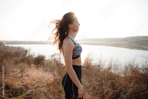 Young woman with athletic body shape standing on high hill