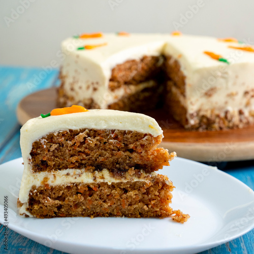 HOME-MADE CARROT CAKE. WITH NUTS AM CARAMEL. BLUE BACKGROUND SLICE