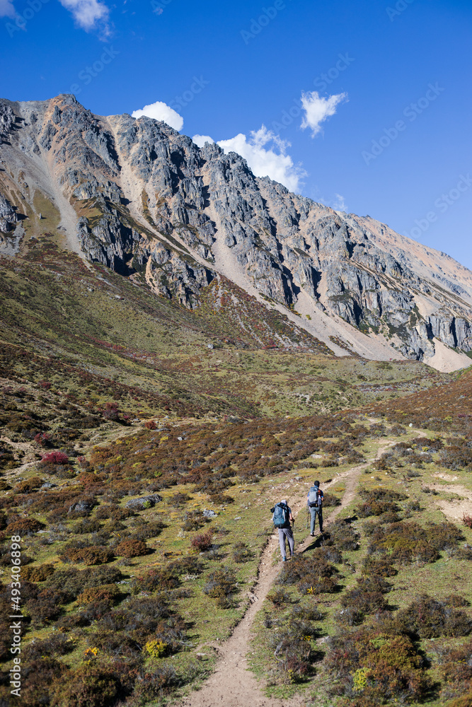 Fototapeta premium Tourists hike toward big rocky mountain in Yunnan