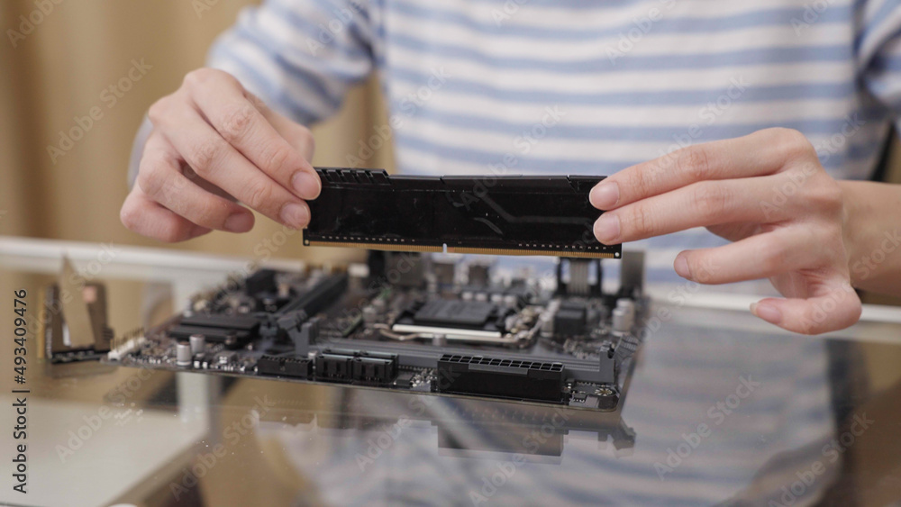 Close-up of a woman removing Random Access Memory (RAM) from a computer motherboard. Close-up of a woman removing Random Access Memory (RAM) from a computer motherboard.