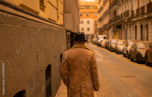 Rear view of man in hat and coat on street during sand storm day. Madrid, Spain