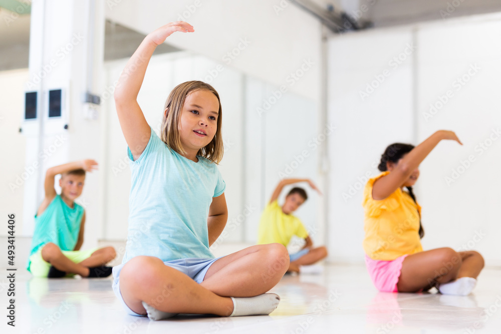 Group of emotional children doing yoga in a dance studio