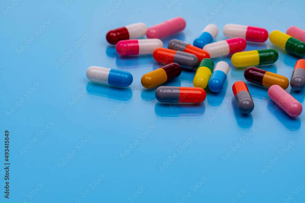 Above view colorful capsule pills on blue background. Prescription drugs. Pharmacology. Healthcare and medicine. Health budget and health policy. Many pills with space. Pharmaceutical industry. Above view colorful capsule pills on blue background. Prescription drugs. Pharmacology. Healthcare and medicine. Health budget and health policy. Many pills with space. Pharmaceutical industry.