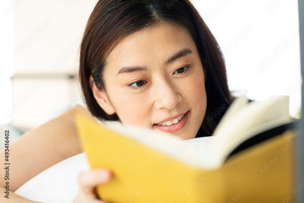 ベッドに横たわり読書をする女性 ベッドに横たわり読書をする女性