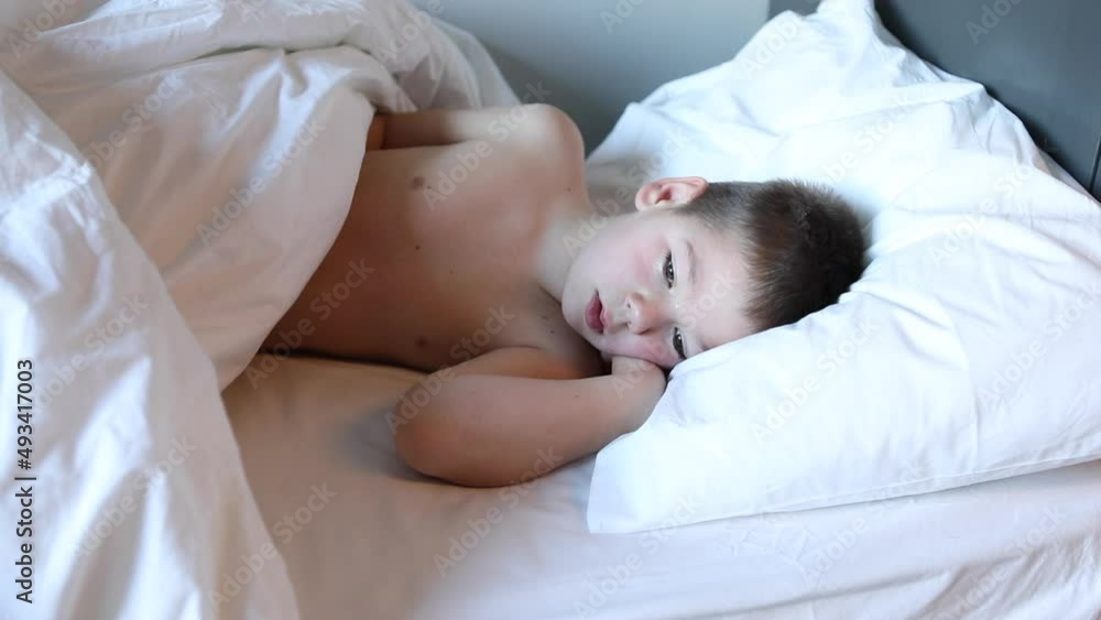 Little boy covering his face with a bed blanket is about to cry being scared of nightmares, ghosts or monsters in his bedroom. Child suffering from sleep disorder concept Little boy covering his face with a bed blanket is about to cry being scared of nightmares, ghosts or monsters in his bedroom. Child suffering from sleep disorder concept
