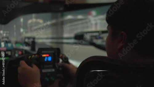 A young man  with  race car video player game with big screen monitors and cockpit controls like a racing car. photo