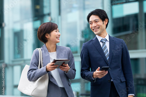 会話しながら歩くビジネススーツの男女