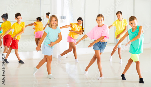 Young girls and boys performing modern dance in studio during rehearsal.