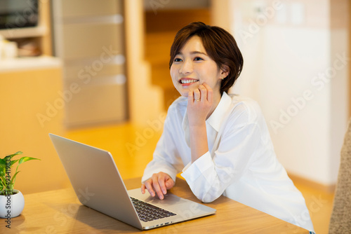 部屋でパソコンを見ながら楽しそうな女性 photo