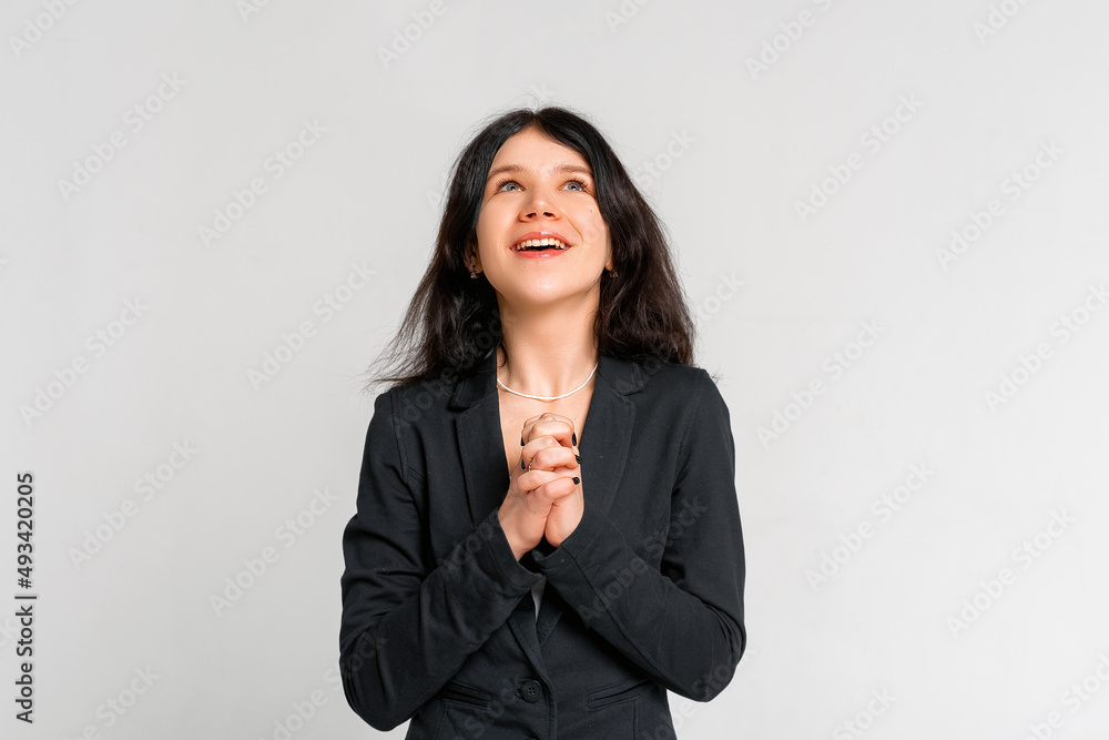 Portrait of beautiful brunette teen gir, hold hands clenched and dreaming, thinking of something, daydreaming, hoping and making wish, anticipating good positive news, grey background Portrait of beautiful brunette teen gir, hold hands clenched and dreaming, thinking of something, daydreaming, hoping and making wish, anticipating good positive news, grey background
