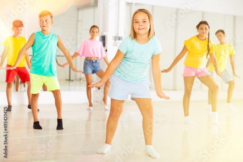 Young girls and boys performing dance in studio during rehearsal.